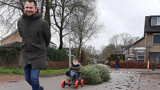 Vader met zoon brengen samen kerstboom naar inzamelpunt